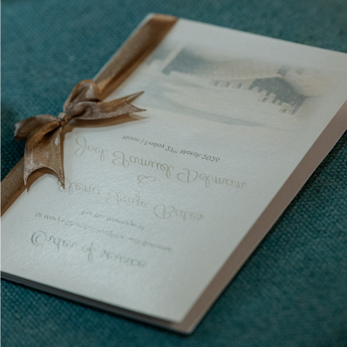 Order of service featuring an illustration of Robin Hood's Bay on the front cover. The booklet is made with card covers and paper inserts, elegantly bound together with a ribbon.